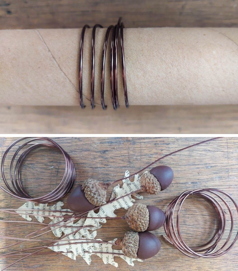 Book page leaves with wire stems, clay acorns and a wire coil on a wooden background