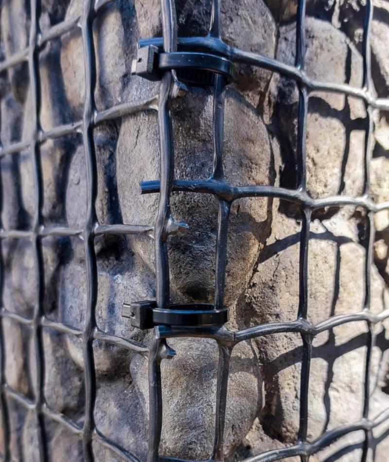 A close up of a cable tie joining wire mesh together.