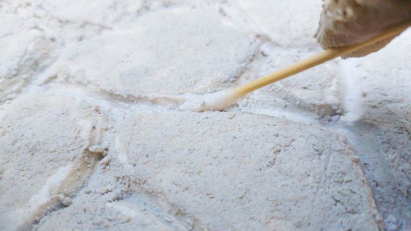 An earbud used to clean up the grooves an gaps between the faux pebbles