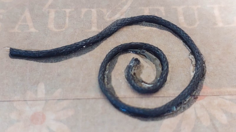 A close up of the waxed cord glued onto a piece of cardboard