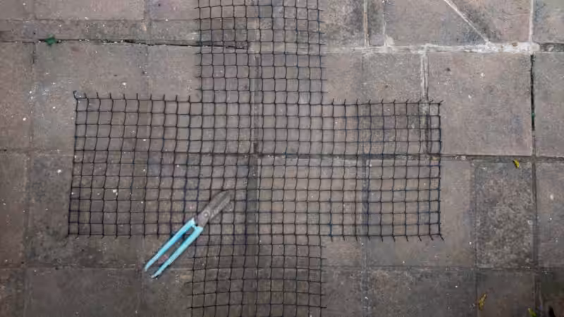 A cross-shaped wire mesh lies on the ground