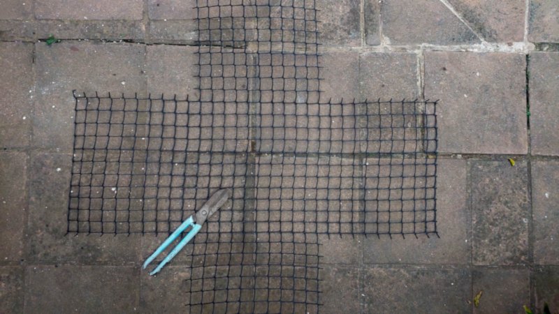 A cross-shaped wire mesh lies on the ground