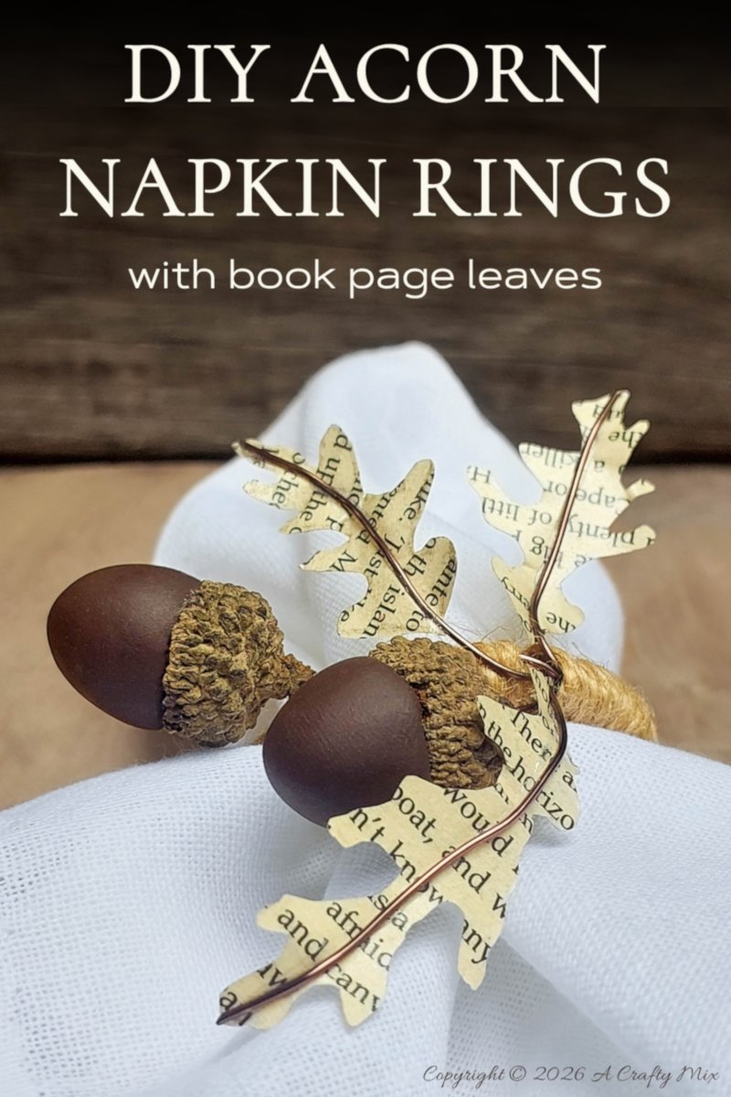 Pinterest graphic for DIY acorn napkin rings with book-page leaves, showing a handmade ring around a white napkin.