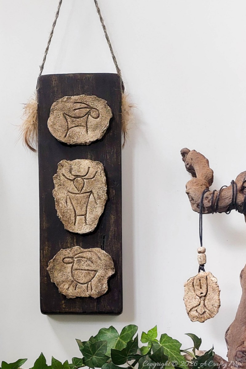 Faux stone petroglyph wall decor mounted on a dark wooden board