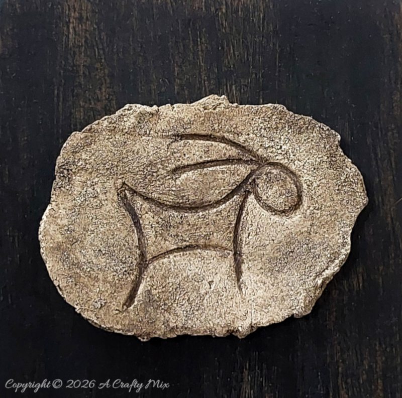 Textured faux stone petroglyph-inspired plaque with horned animal symbol