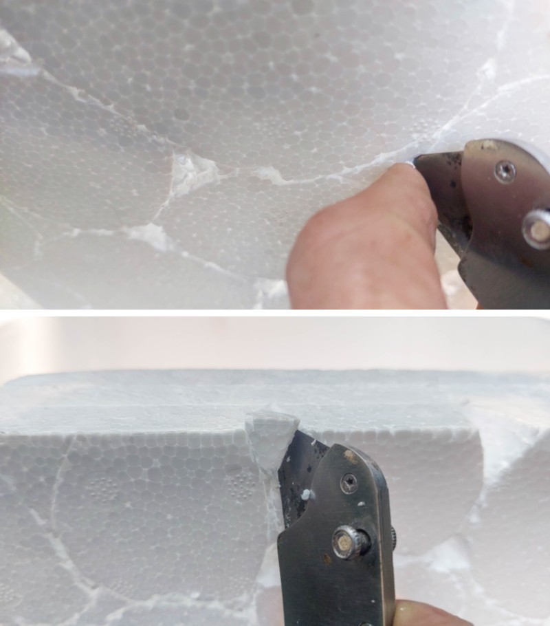 A hand holding a craft knife and removing pieces of foam
