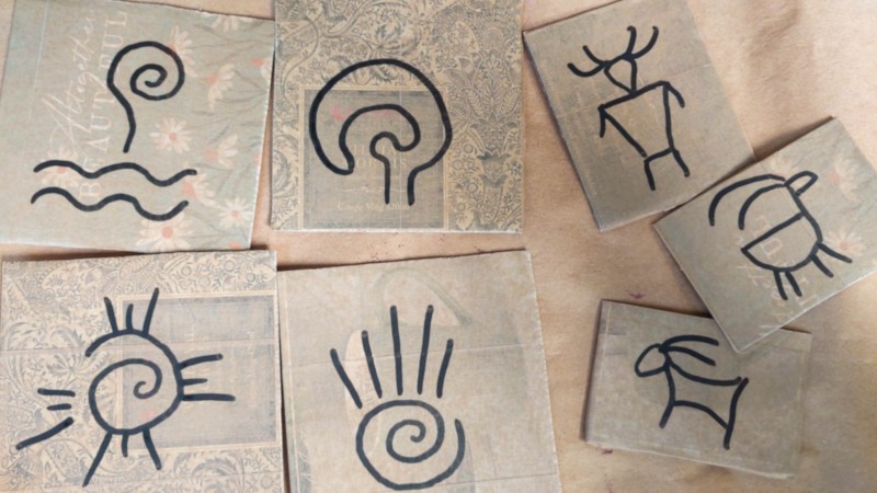 A collection of hand drawn petroglyphs on cardboard
