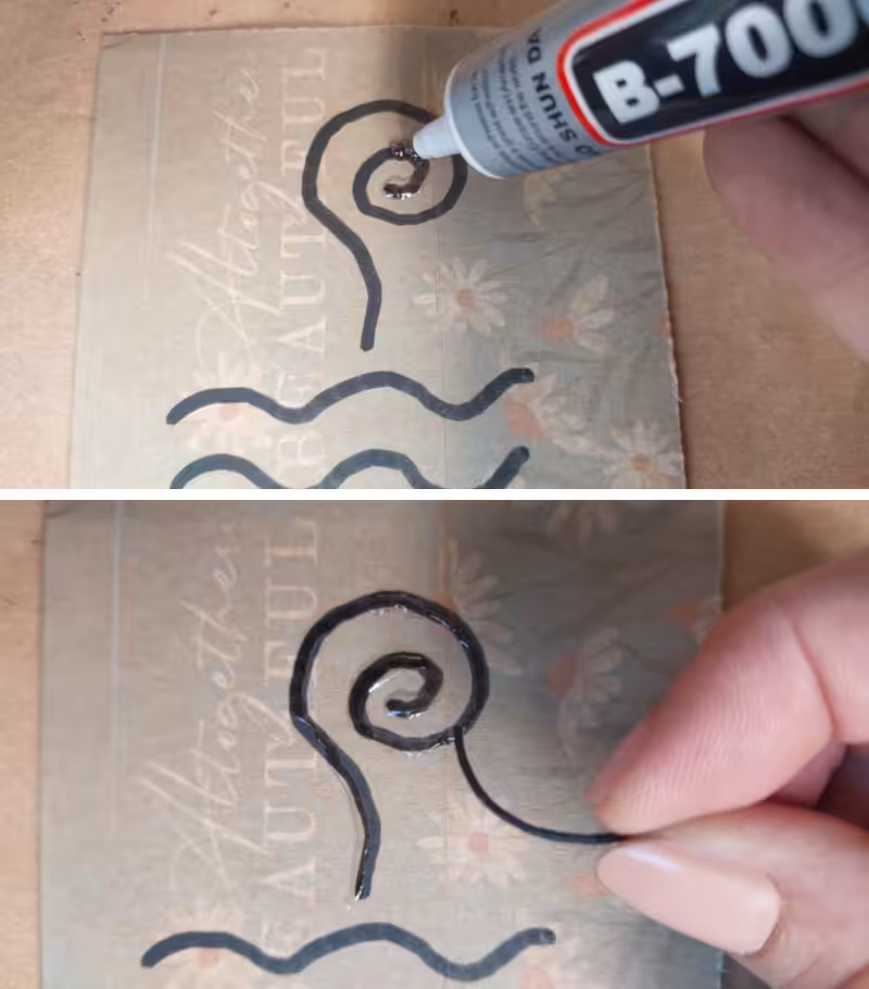 A hand gluing down was cord onto a piece of cardboard