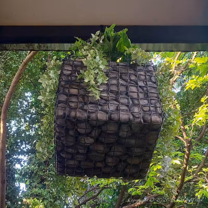 Underside of a lightweight hanging gabion planter showing the wire-mesh base and faux stone finish