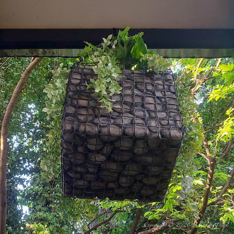 Underside of a lightweight hanging gabion planter showing the wire-mesh base and faux stone finish