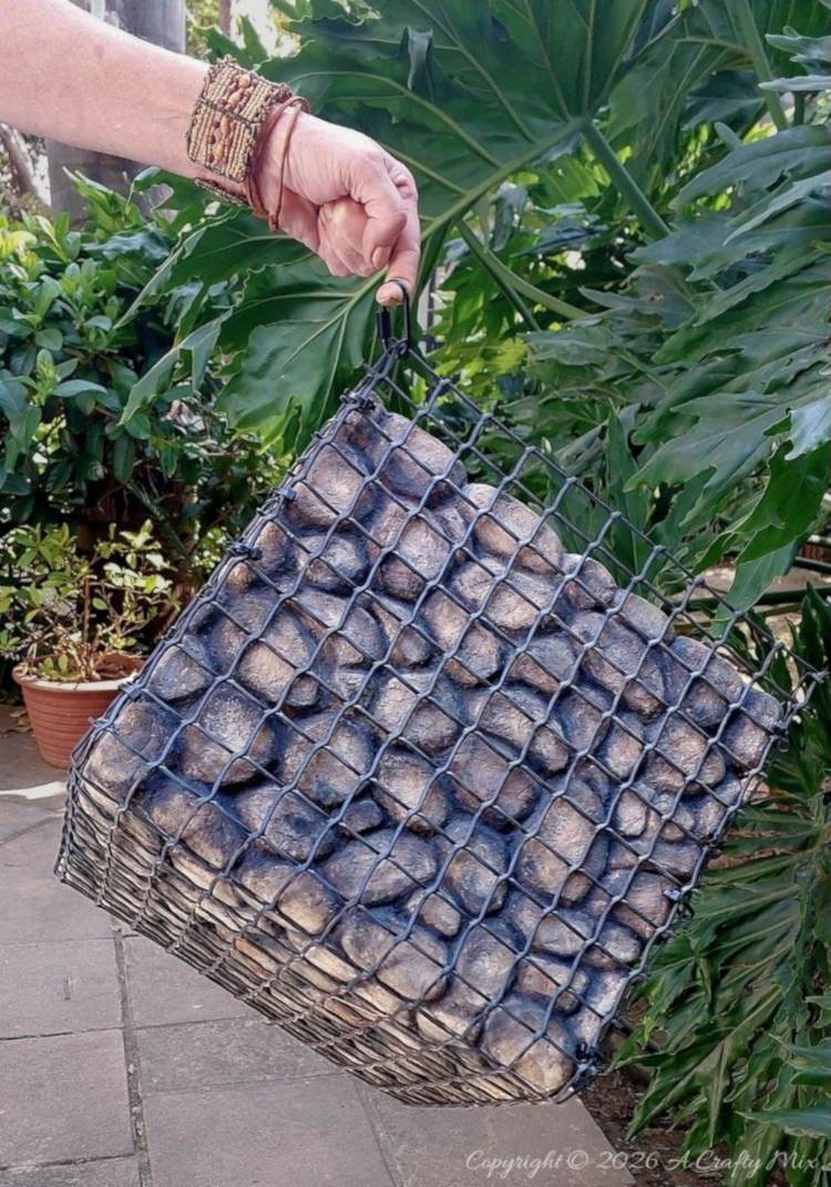 Hand holding a large lightweight gabion planter filled with faux rocks before adding plants