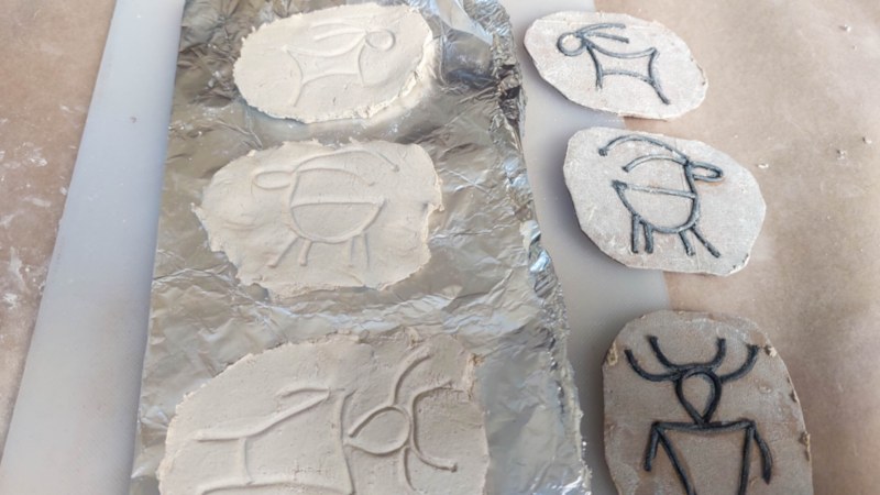 Three petroglyph-inspired clay discs on foil