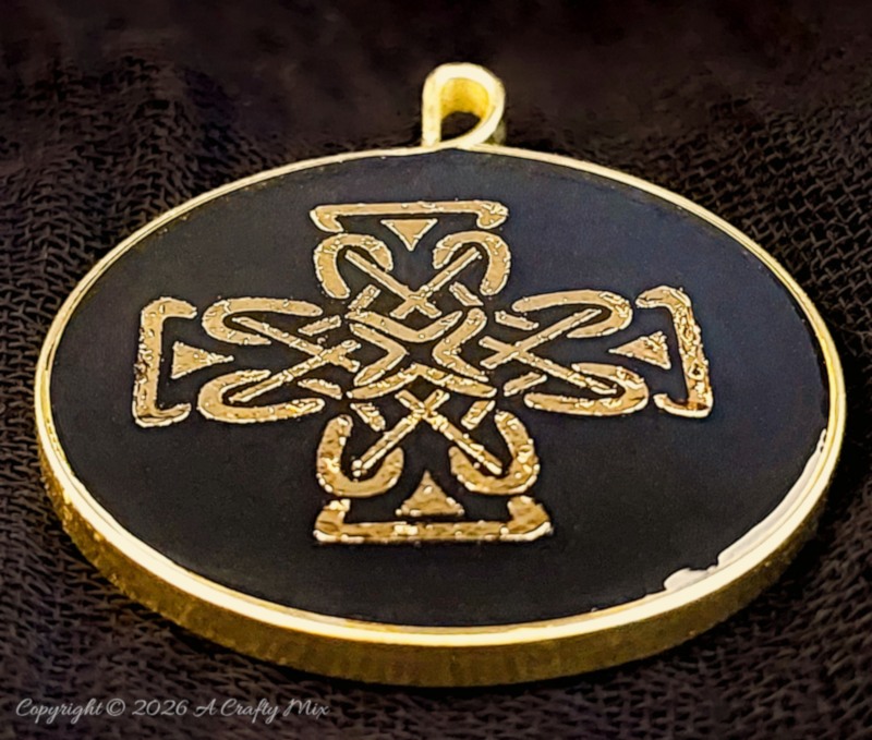 Round handmade resin pendant with a gold Celtic knot design, black background, gold edge, and small hanging loop.