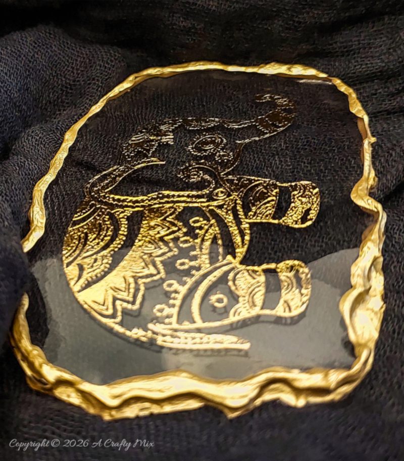 Side view of a clear resin elephant keepsake showing its thick textured gold edge and layered resin surface.